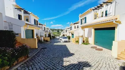 a cobblestone street with white houses and a blue garage at Albufeira Home Paderne in Paderne