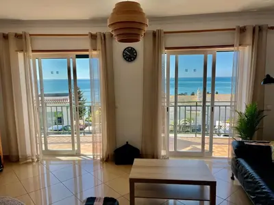 a living room with sliding glass doors with a view of the ocean at Hofnar Sea View Apartment in Albufeira
