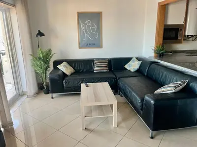 a living room with a black leather couch and a coffee table at Hofnar Sea View Apartment in Albufeira