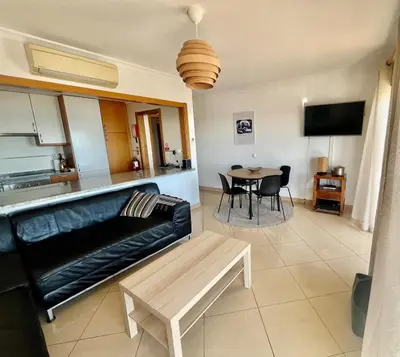a living room with a black leather couch and a table at Hofnar Sea View Apartment in Albufeira