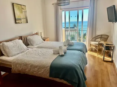 two beds in a bedroom with a view of the ocean at Hofnar Sea View Apartment in Albufeira