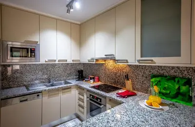 a kitchen with white cabinets and granite counter tops at Apartamento Laurus in Albufeira