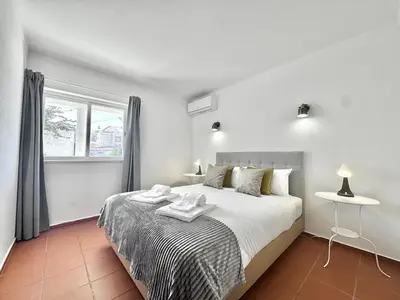 a bedroom with a bed with white sheets and a window at Beach 15 min away! - Rustic with AC and WiFi in Quarteira