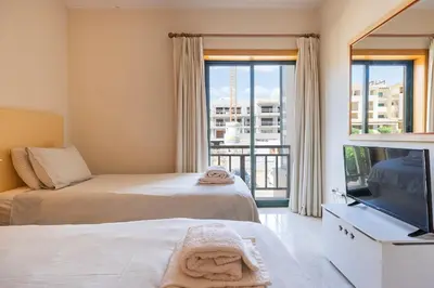 a bedroom with two beds and a tv and a balcony at Vilamoura Residence in Quarteira