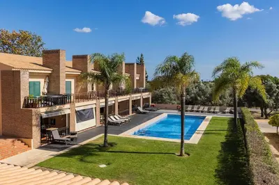 an exterior view of a house with a swimming pool and palm trees at Vilamoura Residence in Quarteira