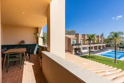 a balcony with a table and chairs and a pool at Vilamoura Residence in Quarteira