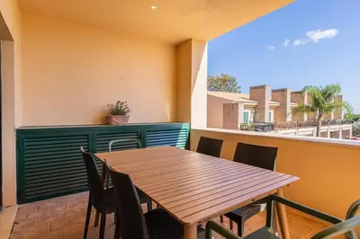 a wooden table and chairs on a balcony at Vilamoura Residence in Quarteira