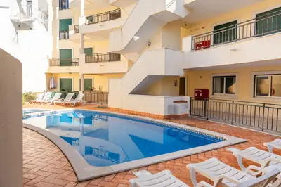 a swimming pool with white chairs next to a building at Old Town Boho Seaview Elegance in Albufeira