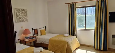 a hotel room with two beds and a window at Sao Rafael Village 2 Bedroom with a Pool in Albufeira