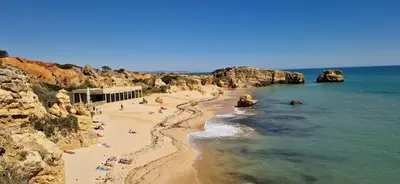 a beach with people laying on the sand and the water at Sao Rafael Village 2 Bedroom with a Pool in Albufeira