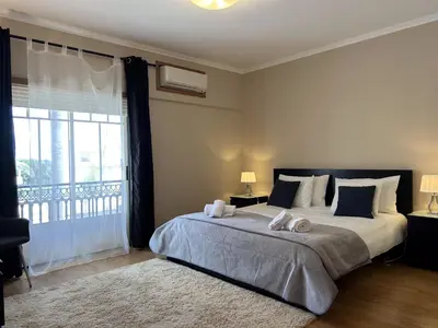 a bedroom with a large bed with a large window at Moradia B - 200m da Praia da Oura - Leste in Albufeira