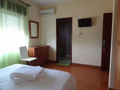 a bedroom with a bed and a chair and a television at Residencial Espadinha in Quarteira