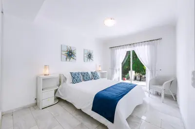 a white bedroom with a bed and a window at Casa Sonhos in Albufeira