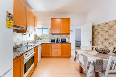 a kitchen with wooden cabinets and a table at Sunny 3BDR Apt with Pool in Ferreiras by LovelyStay in Albufeira