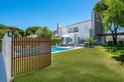 a fence in front of a yard with a pool at Villa Celeste by SAPvillas in Vilamoura