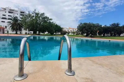 a swimming pool with two metal hand rails next to it at Brand New Studio in Rua da Oura in Albufeira