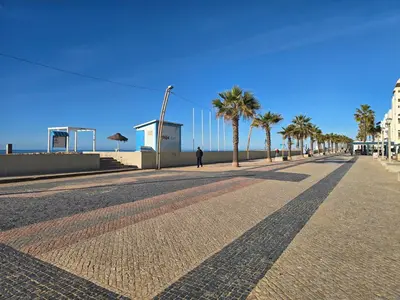 a street with palm trees and a person walking down the street at Modern Beach Apartment - Avenida Mar 2 - 150 mts da praia in Quarteira