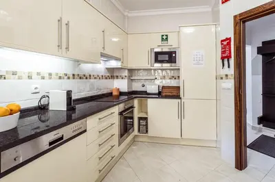 a kitchen with white cabinets and black counter tops at Albufeira Vista Marina Apt - Old Town in Albufeira