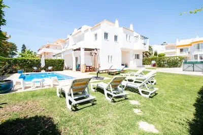 a yard with chairs and a pool in front of a house at Vila Anna in Albufeira
