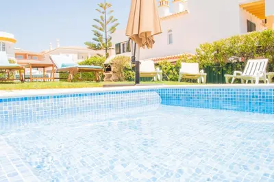 a swimming pool in a villa with an umbrella at Vila Anna in Albufeira