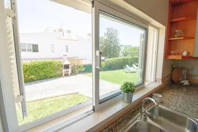a kitchen window with a view of a yard at Vila Anna in Albufeira