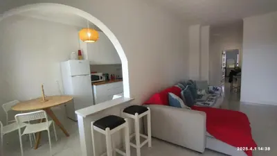 a kitchen with a wooden table and a white refrigerator at Quarteira First Line Front Beach Pool Flat View in Quarteira