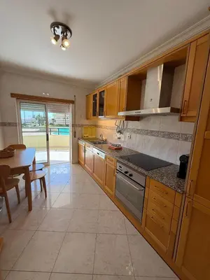 a kitchen with wooden cabinets and a table and a dining room at Galé Mar By Albufeira Rental in Albufeira