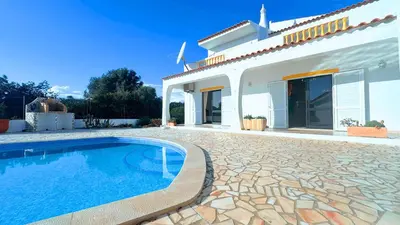 a villa with a swimming pool in front of a house at Casa das ficus in Guia