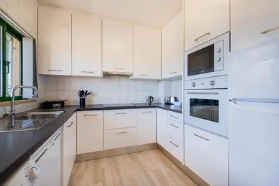 a white kitchen with white cabinets and a sink at Azinhais Apartment - Heart of Oura in Albufeira