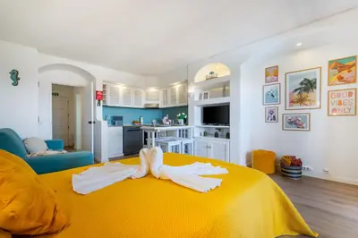 a bedroom with a yellow bed and a kitchen at NEW! Perfect Studio with Swimming Pool in Albufeira