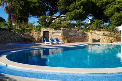 a swimming pool with two blue chairs and a wall at Stanchion Apartment in Albufeira