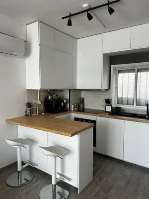 a white kitchen with white cabinets and bar stools at Quarteira Beach Home Haven in Quarteira