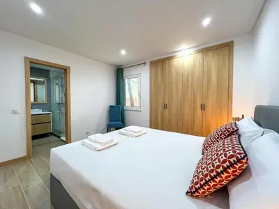 a bedroom with a white bed with pillows on it at Modern Retreat 700m from the Beach - Salgados in Guia