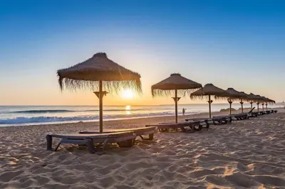 a line of beach chairs with umbrellas on the beach at Modern Retreat 700m from the Beach - Salgados in Guia