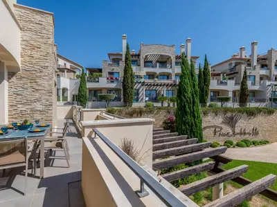 a patio with a table and chairs and a building at Apartment Pine Hills Reva Santuary Modern Elegance by Interhome in Vilamoura
