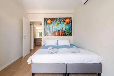 a bedroom with a bed with a painting on the wall at Casa Eden 2BR modern Apartment near Marina! Patio-Porch-WS-BBQ-FAST WIFI! in Quarteira
