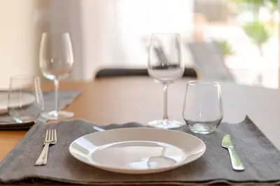 a table with a plate and wine glasses on it at Casa Eden 2BR modern Apartment near Marina! Patio-Porch-WS-BBQ-FAST WIFI! in Quarteira