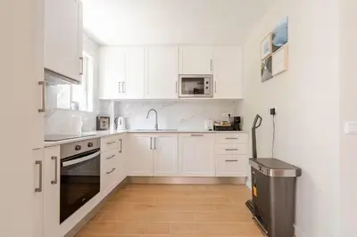 a white kitchen with white cabinets and a trash can at Casa Eden 2BR modern Apartment near Marina! Patio-Porch-WS-BBQ-FAST WIFI! in Quarteira