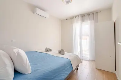 a white bedroom with a blue bed and a window at Casa Eden 2BR modern Apartment near Marina! Patio-Porch-WS-BBQ-FAST WIFI! in Quarteira