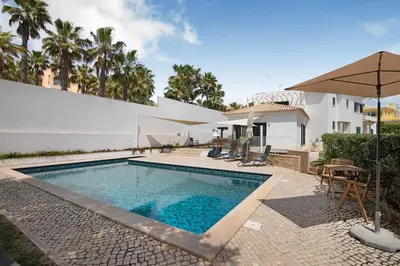 a swimming pool with an umbrella next to a house at Al´Corais in Albufeira