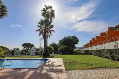 a swimming pool with a palm tree and a building at Jardins do Castelo - Piscina e tranquilidade - BY BEDZY in Albufeira