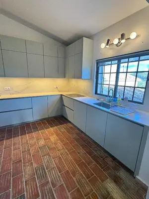 a kitchen with white cabinets and a wooden floor at Casa da Parreira in Loulé