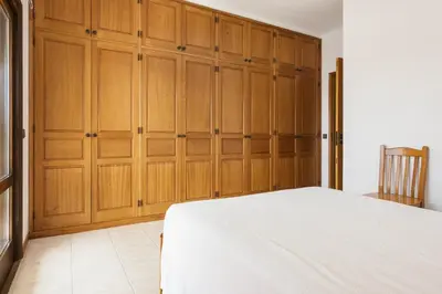a bedroom with wooden cabinets and a white bed at Vila de santa Eulalia II - Albufeira in Albufeira