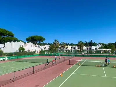 a group of people playing tennis on a tennis court at Balaia Golf Village T2 a 10 minutos da praia in Olhos de Água