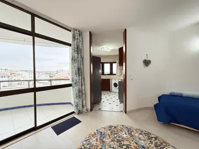 a living room with a blue couch and a large window at Home Out Albufeira - T1 Oura in Albufeira