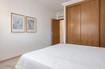 a bedroom with a white bed and a wooden cabinet at Praia Village II - Peaceful condominium by HD in Vilamoura