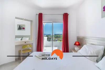 a bedroom with a bed and a window with red curtains at #314 T2 Serenity by Home Holidays in Albufeira