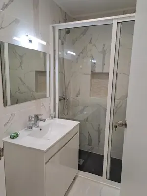 a white bathroom with a sink and a shower at Apartamento T1 a 10m da praia Quarteira in Quarteira
