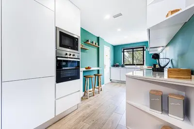a kitchen with white cabinets and blue walls at Apartamento T3 Praia da Falésia - PINE SUN PARK in Albufeira