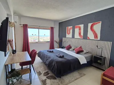 a bedroom with a king sized bed and a window at Albufeira Cozy Sea View with Balcony & Resort Access in Albufeira